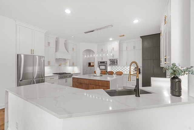 kitchen featuring appliances with stainless steel finishes, sink, white cabinets, and custom range hood