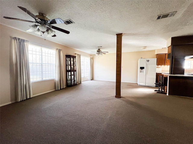 unfurnished living room with carpet, a textured ceiling, and ceiling fan