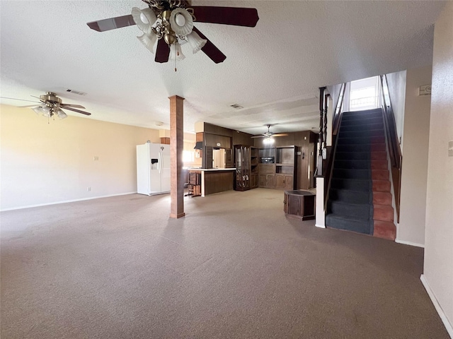 unfurnished living room featuring ceiling fan, decorative columns, and a textured ceiling