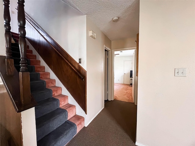 stairs with carpet flooring and a textured ceiling