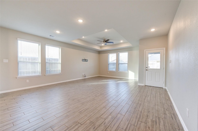 interior space with a tray ceiling, light hardwood / wood-style flooring, and ceiling fan