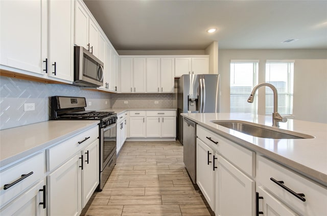 kitchen with tasteful backsplash, sink, stainless steel appliances, and white cabinets