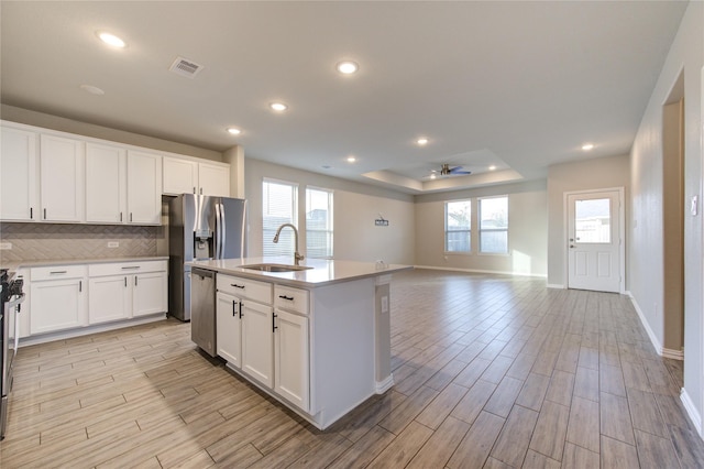 kitchen featuring white cabinetry, appliances with stainless steel finishes, sink, and a center island with sink