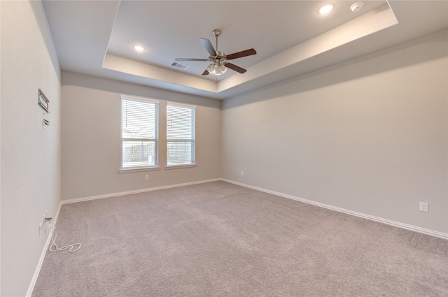 empty room featuring ceiling fan, a tray ceiling, and carpet flooring