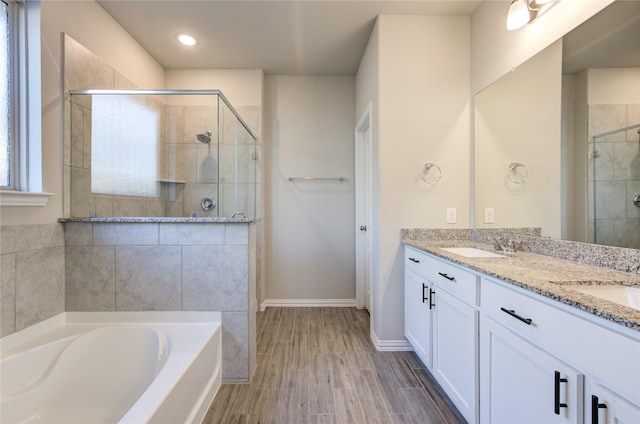 bathroom featuring vanity, hardwood / wood-style flooring, and plus walk in shower