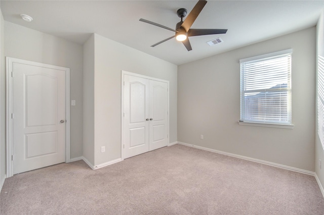 unfurnished bedroom featuring light colored carpet, a closet, and ceiling fan