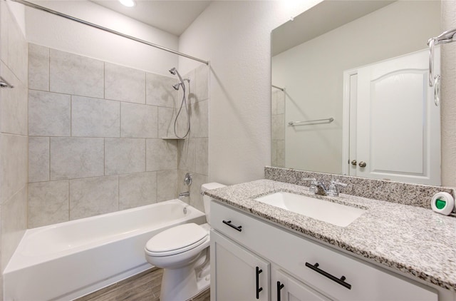 full bathroom featuring vanity, toilet, tiled shower / bath combo, and hardwood / wood-style floors