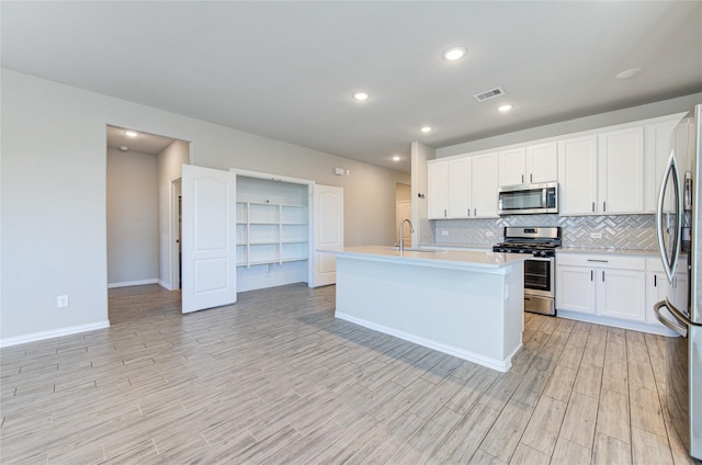 kitchen with sink, light hardwood / wood-style flooring, stainless steel appliances, an island with sink, and white cabinets