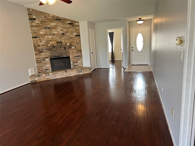 foyer entrance featuring ceiling fan, lofted ceiling, a fireplace, and light hardwood / wood-style flooring