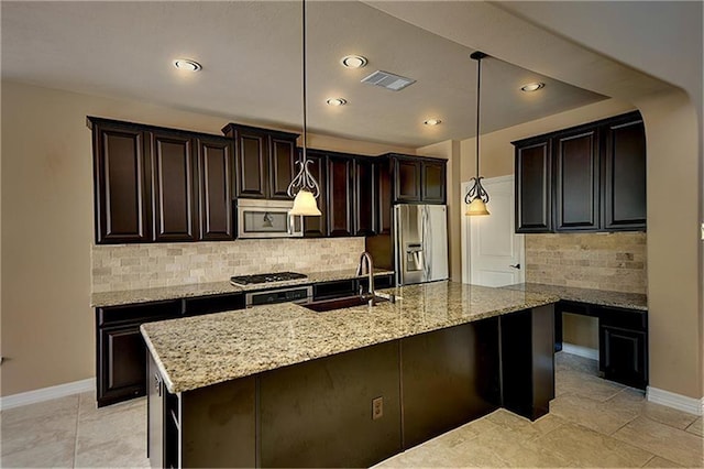 kitchen featuring appliances with stainless steel finishes, an island with sink, sink, hanging light fixtures, and dark brown cabinetry