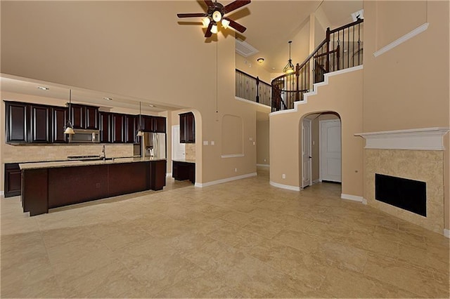 unfurnished living room with sink, a tile fireplace, and ceiling fan