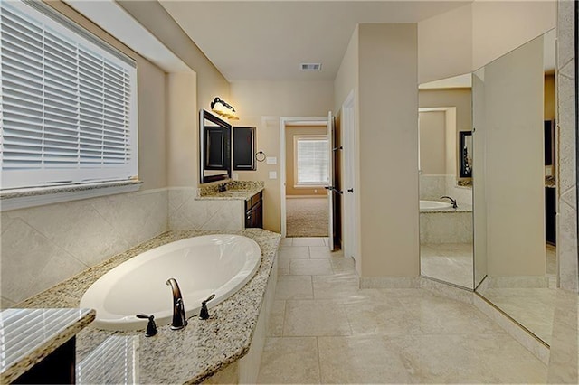 bathroom with vanity and tiled bath