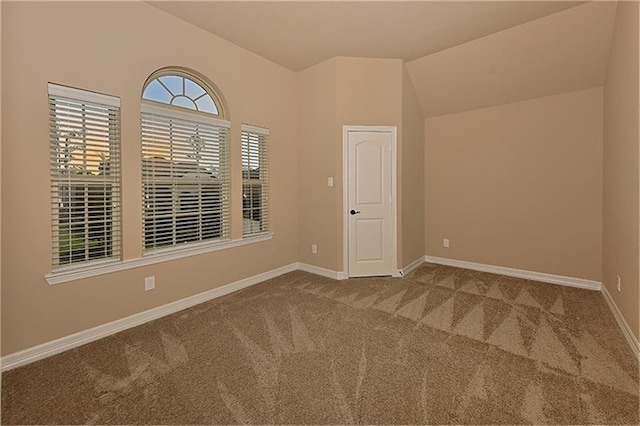 carpeted spare room featuring vaulted ceiling