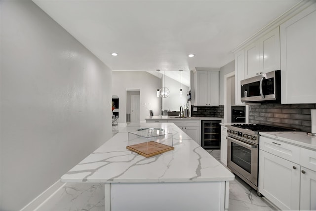 kitchen with appliances with stainless steel finishes, white cabinetry, wine cooler, hanging light fixtures, and light stone counters