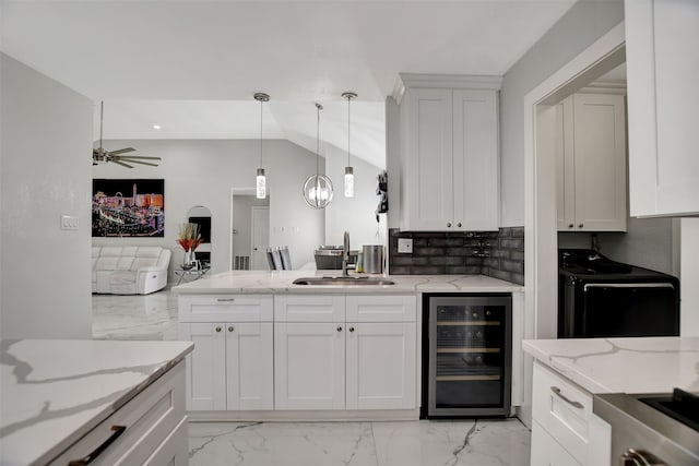 kitchen with pendant lighting, white cabinetry, sink, beverage cooler, and light stone counters