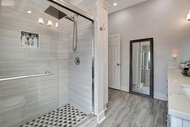 bathroom featuring a shower with door and vanity