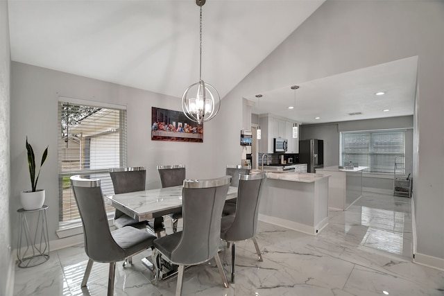 dining space featuring an inviting chandelier, high vaulted ceiling, and sink