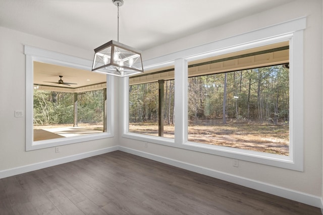 unfurnished dining area with dark wood-type flooring, plenty of natural light, and a chandelier