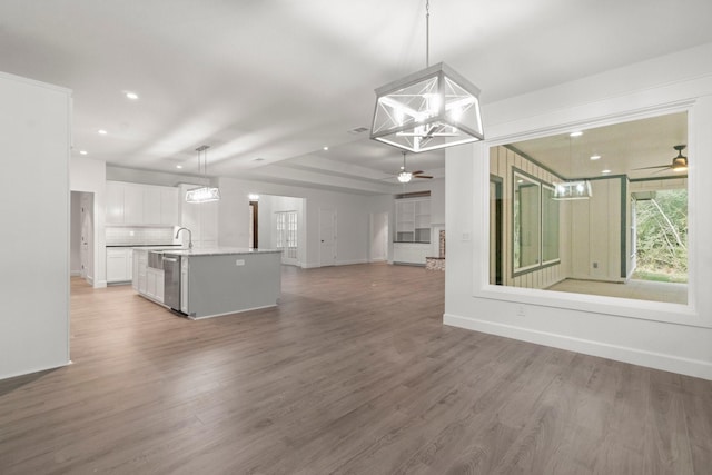 kitchen with ceiling fan with notable chandelier, decorative light fixtures, dishwasher, white cabinets, and a kitchen island with sink