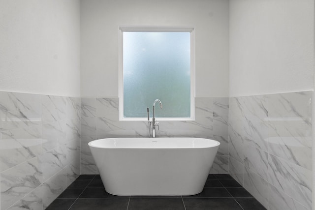 bathroom with tile patterned flooring, a bathing tub, and tile walls