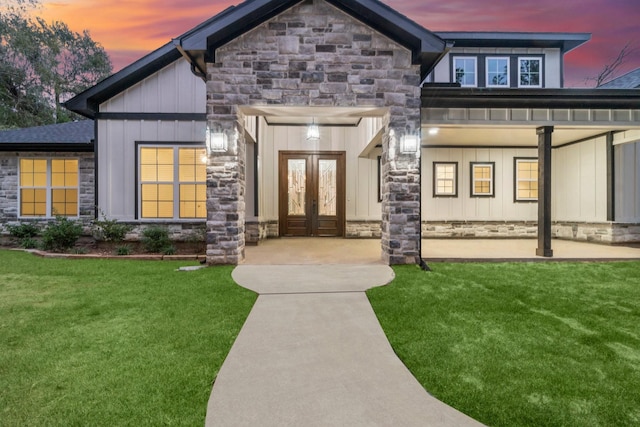 exterior entry at dusk featuring a lawn and french doors