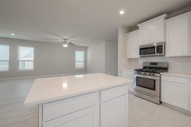 kitchen with a kitchen island, white cabinetry, appliances with stainless steel finishes, and tasteful backsplash