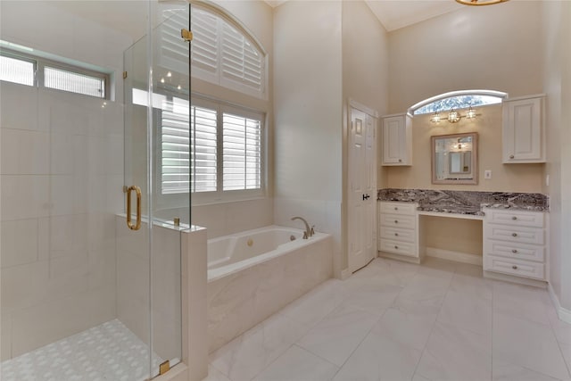 bathroom with a towering ceiling, vanity, and plus walk in shower