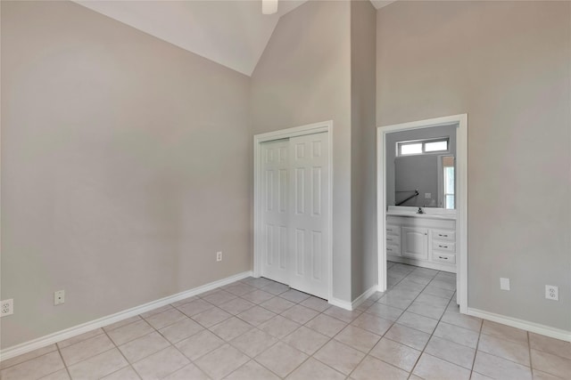 unfurnished bedroom with connected bathroom, high vaulted ceiling, a closet, and light tile patterned flooring