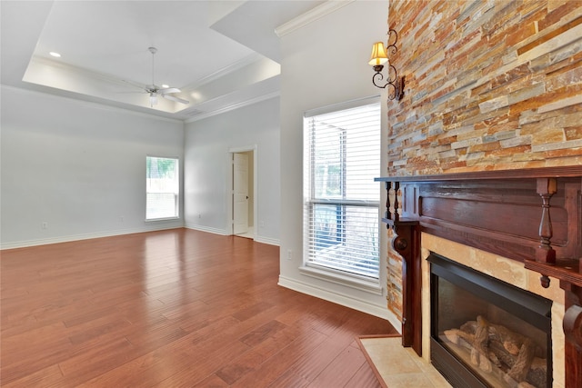 unfurnished living room featuring wood-type flooring, ornamental molding, a raised ceiling, and ceiling fan