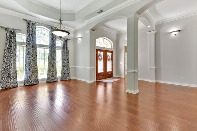 entrance foyer featuring dark wood-type flooring, a towering ceiling, crown molding, and ornate columns