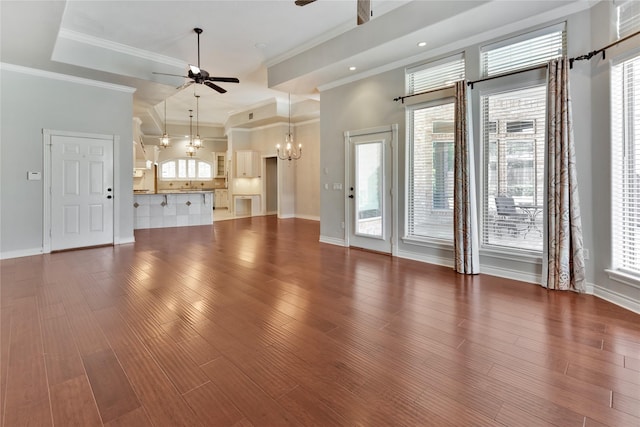 unfurnished living room with ornamental molding, wood-type flooring, ceiling fan with notable chandelier, and plenty of natural light