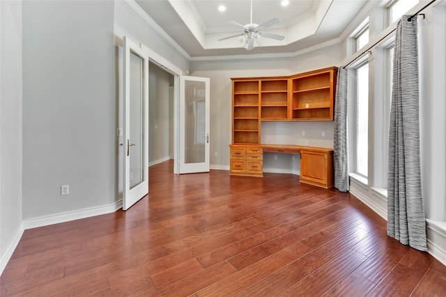 unfurnished office featuring ornamental molding, dark hardwood / wood-style floors, built in desk, and a healthy amount of sunlight