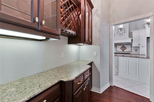 kitchen with tasteful backsplash, dark hardwood / wood-style flooring, light stone counters, and decorative light fixtures