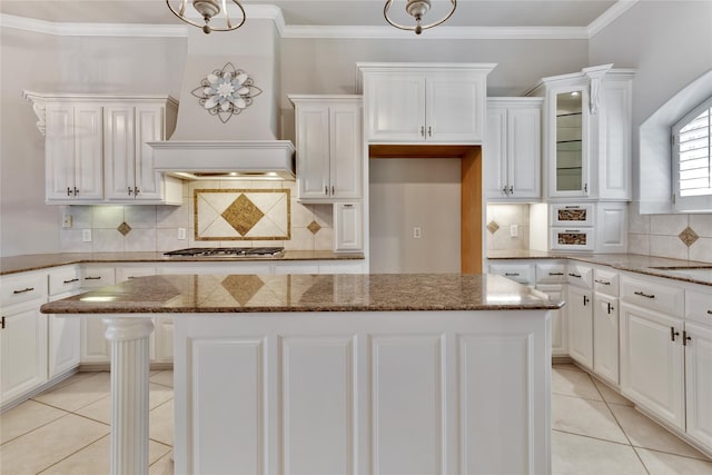 kitchen featuring white cabinetry, stone countertops, a kitchen island, and custom range hood