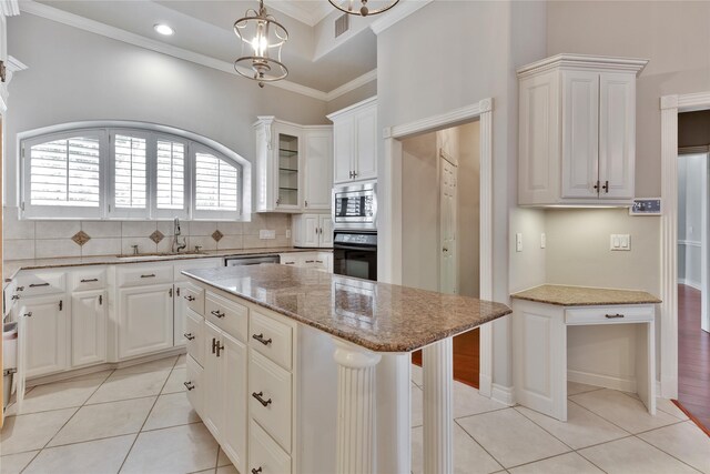 kitchen with a kitchen island, stainless steel microwave, decorative light fixtures, sink, and oven