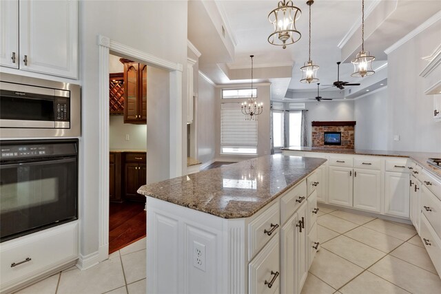 kitchen with decorative light fixtures, a center island, stainless steel microwave, oven, and white cabinets