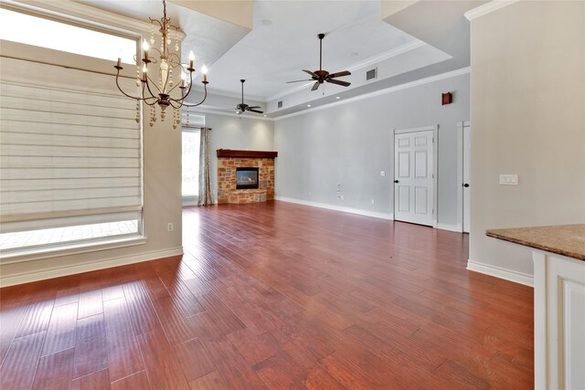 unfurnished living room featuring a raised ceiling, wood-type flooring, crown molding, and a fireplace