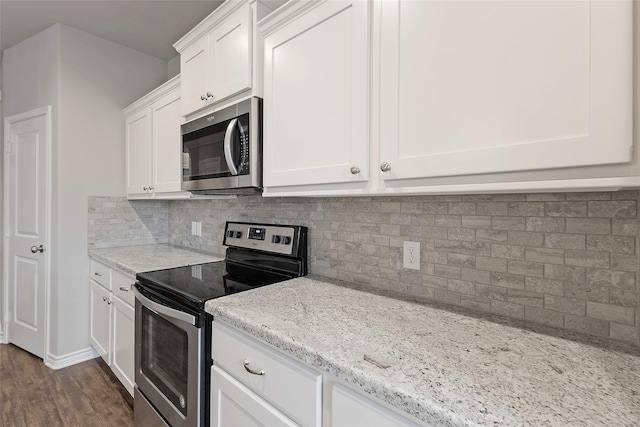 kitchen with appliances with stainless steel finishes, backsplash, light stone countertops, white cabinets, and dark hardwood / wood-style flooring