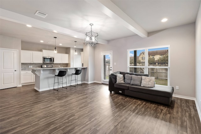 living room with dark hardwood / wood-style floors, beam ceiling, and an inviting chandelier