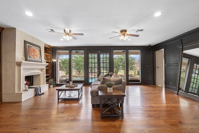 living room with french doors, a premium fireplace, hardwood / wood-style floors, and a textured ceiling