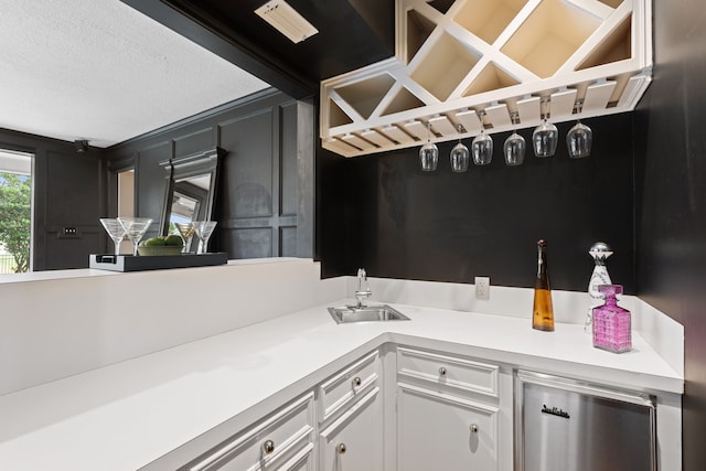 kitchen featuring white cabinetry, sink, wine cooler, and a textured ceiling