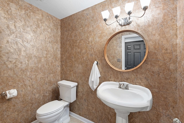 bathroom with sink, a textured ceiling, a chandelier, and toilet