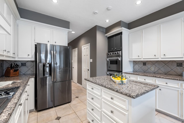 kitchen featuring appliances with stainless steel finishes, tasteful backsplash, white cabinetry, a center island, and light tile patterned floors