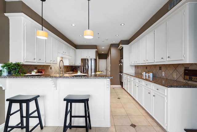 kitchen featuring light tile patterned floors, dark stone countertops, appliances with stainless steel finishes, pendant lighting, and white cabinets