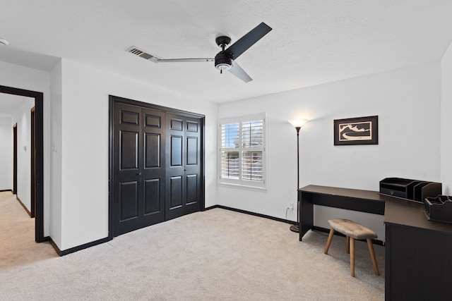 carpeted home office featuring a textured ceiling and ceiling fan