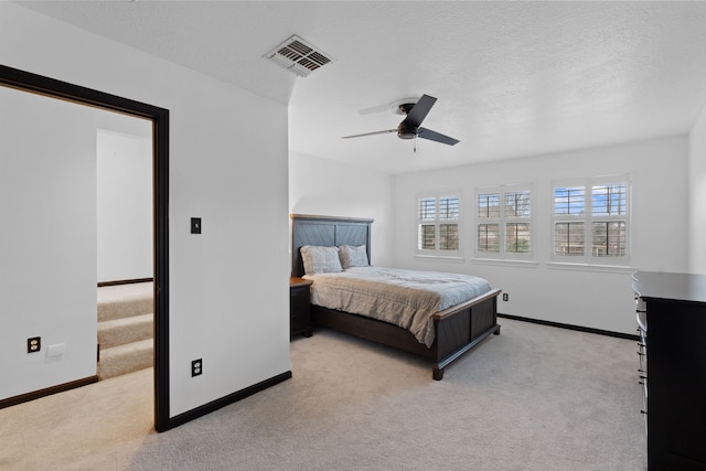 carpeted bedroom with ceiling fan and a textured ceiling