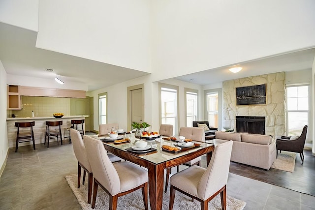 dining room with a stone fireplace and light tile patterned floors