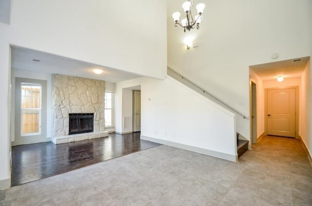 unfurnished living room with a notable chandelier, a fireplace, and a high ceiling