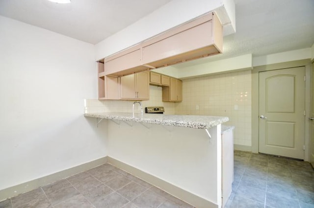 kitchen featuring a kitchen bar, sink, light brown cabinets, kitchen peninsula, and decorative backsplash