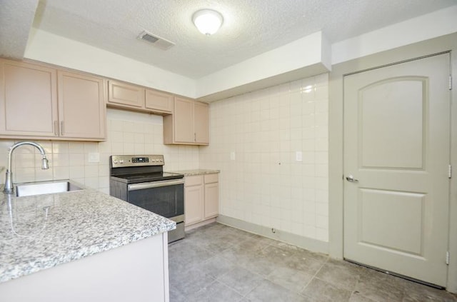 kitchen with sink, light stone counters, light brown cabinets, a textured ceiling, and stainless steel electric range